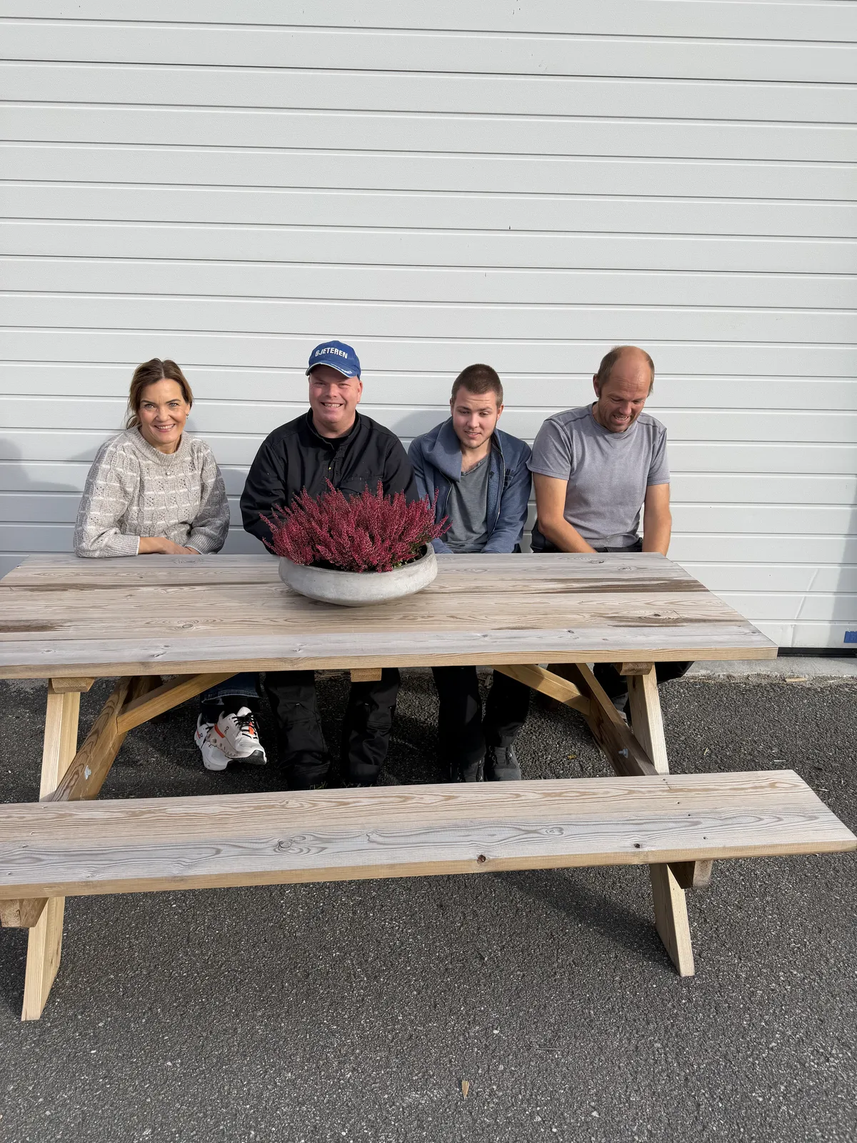 Fire ansatte sitter bak et hagebord produsert hos SQP